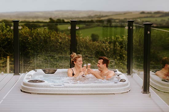 Couple Sat in Midsomer Lodges Hot Tub overlooking glastonbury